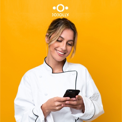 Ragazza vestita da chef che guarda sorridendo lo schermo dello smartphone
